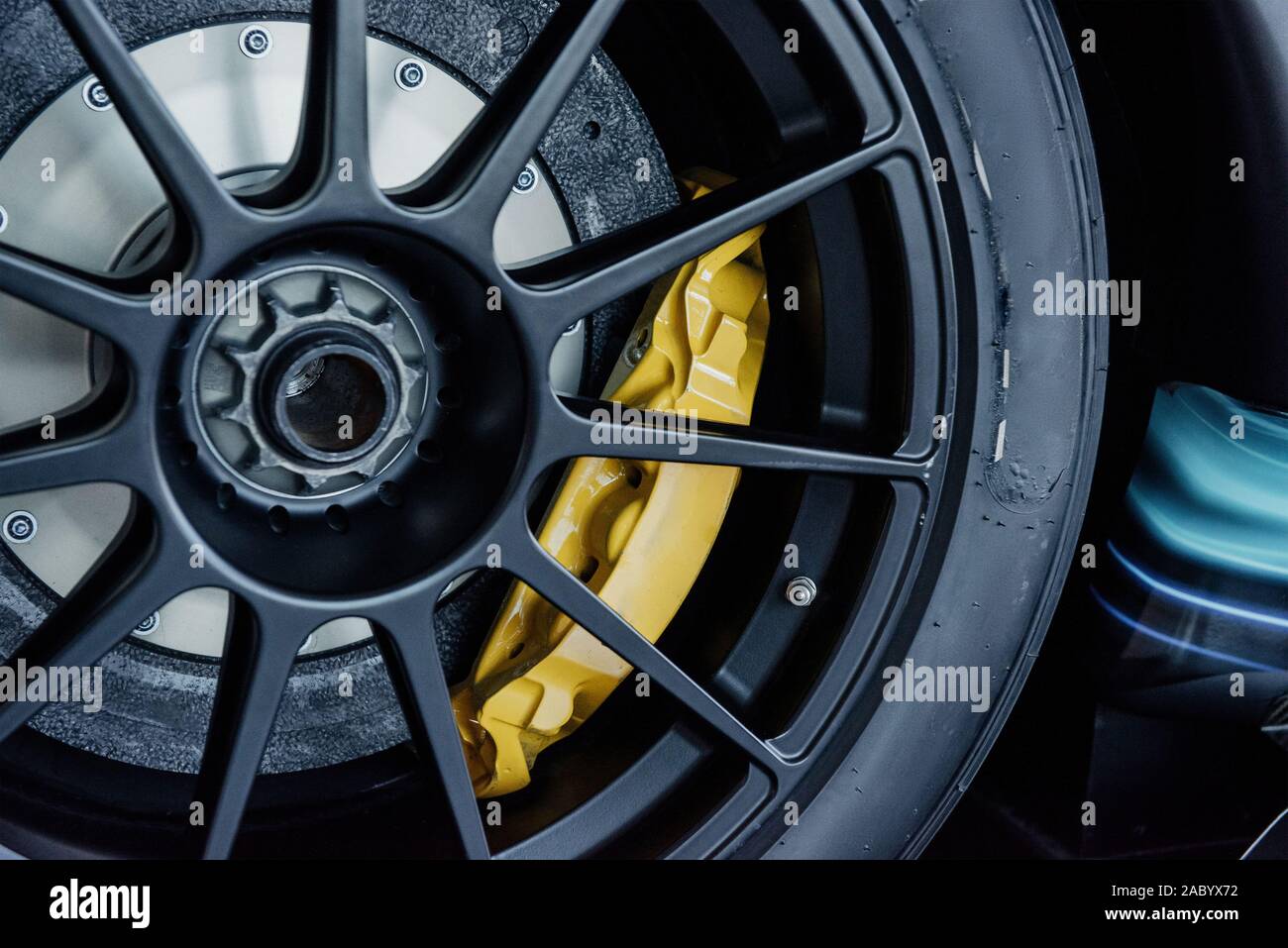 Immagine ravvicinata di nero ruote in lega leggera con giallo disco freno pad, di basso profilo e di pneumatici di un automobile Foto Stock