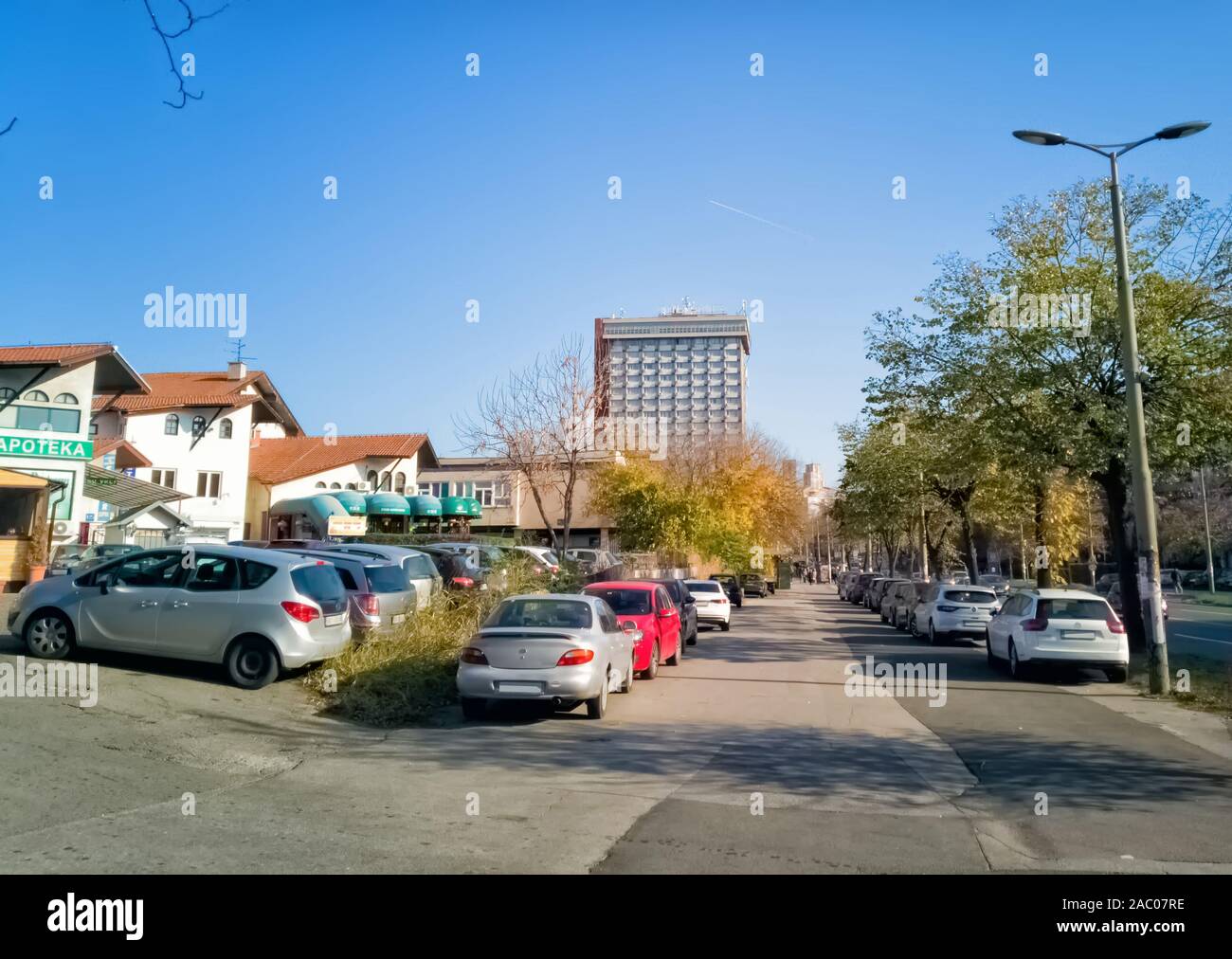 Ustanicka, Vozdovac, Belgrado, Serbia - Novembre 25, 2019: street view, marciapiede e parcheggio con case e hotel Serbia grattacielo a distanza Foto Stock