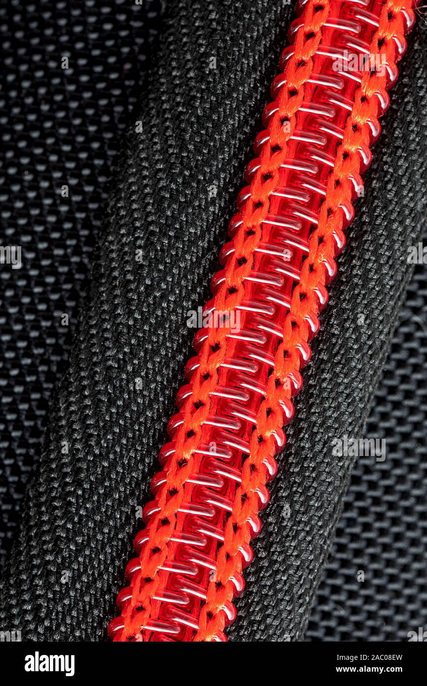In prossimità di una parte di un rosso zip in plastica cucita in una matita nera caso Foto Stock