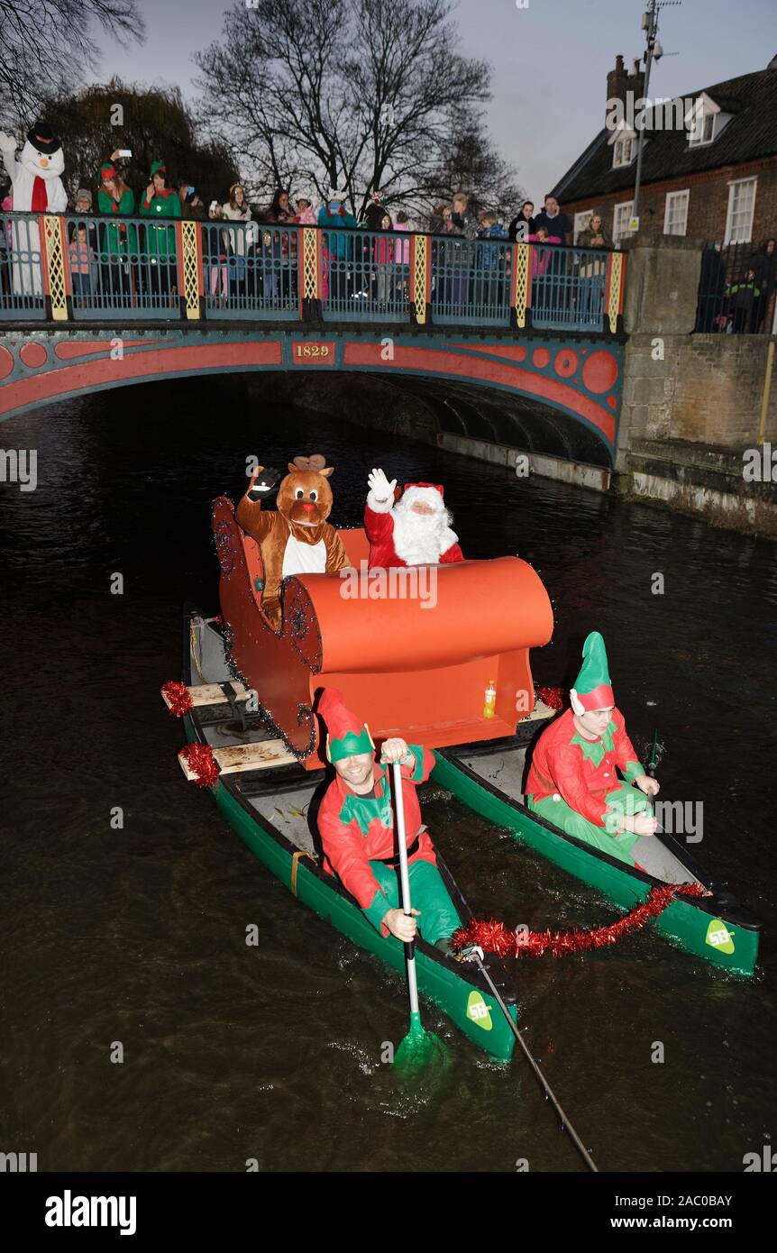 Babbo Natale arriva con la slitta barca sotto la città ponte in ferro, tirato dal canottaggio elfi sul piccolo fiume Ouse, a Thetford. Foto Stock