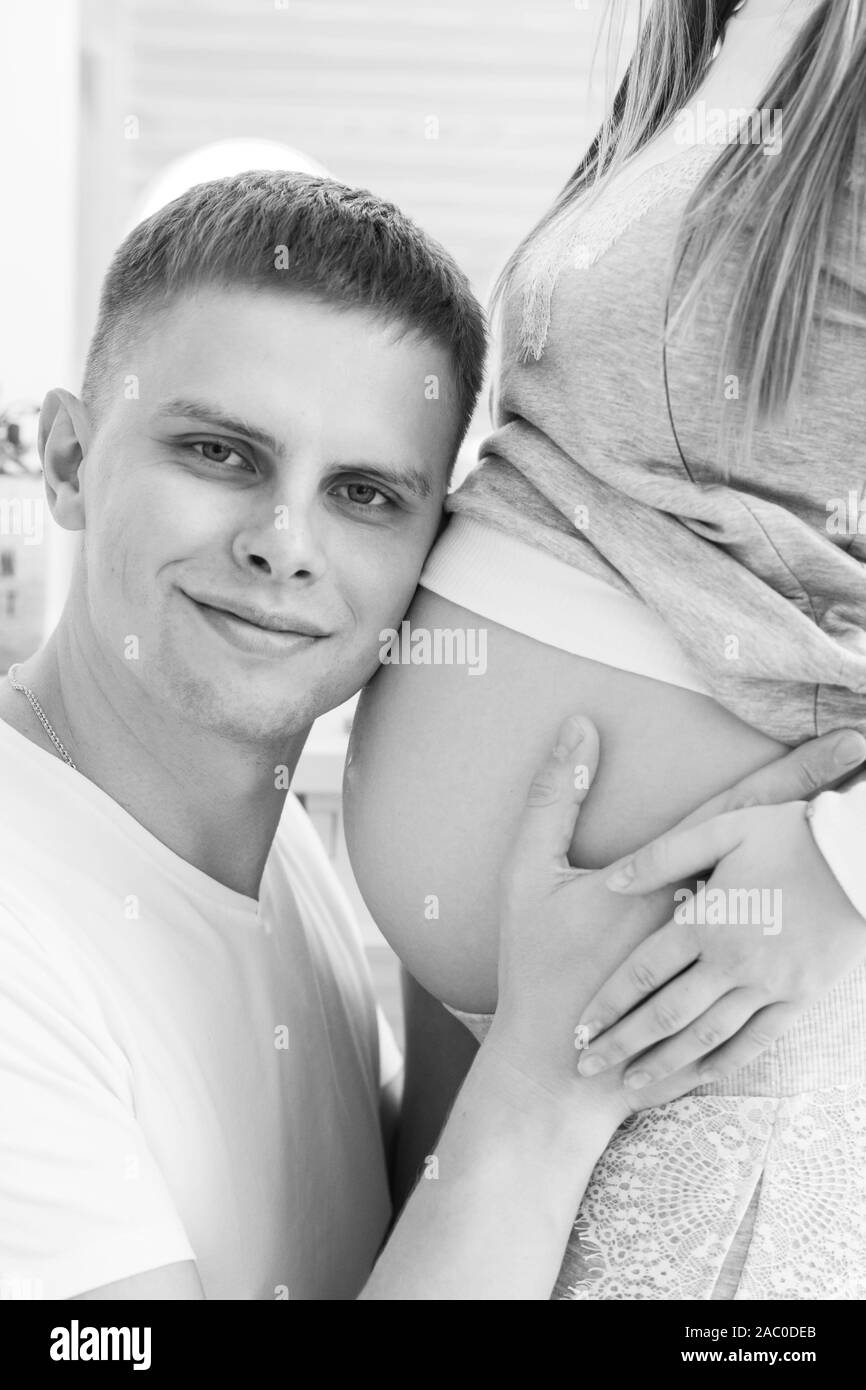Coppia giovane - uomo e donna in attesa di un bambino, trascorrere del tempo insieme, marito abbracci a sua moglie il ventre e baci. Foto Stock