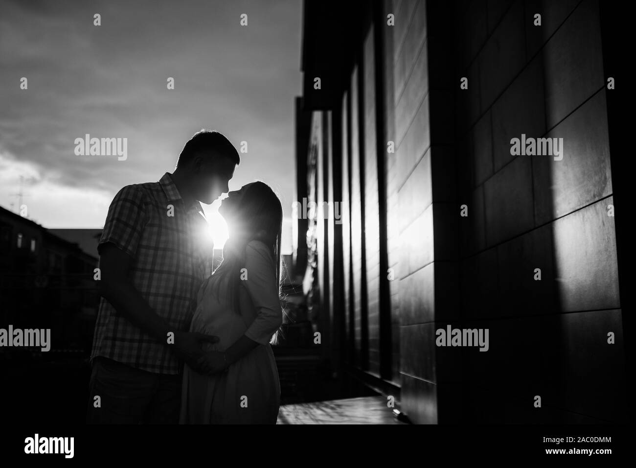 Coppia giovane - uomo e donna in attesa di un bambino, trascorrere del tempo insieme sulla strada della citta' al tramonto. In attesa della nascita di un bambino Foto Stock