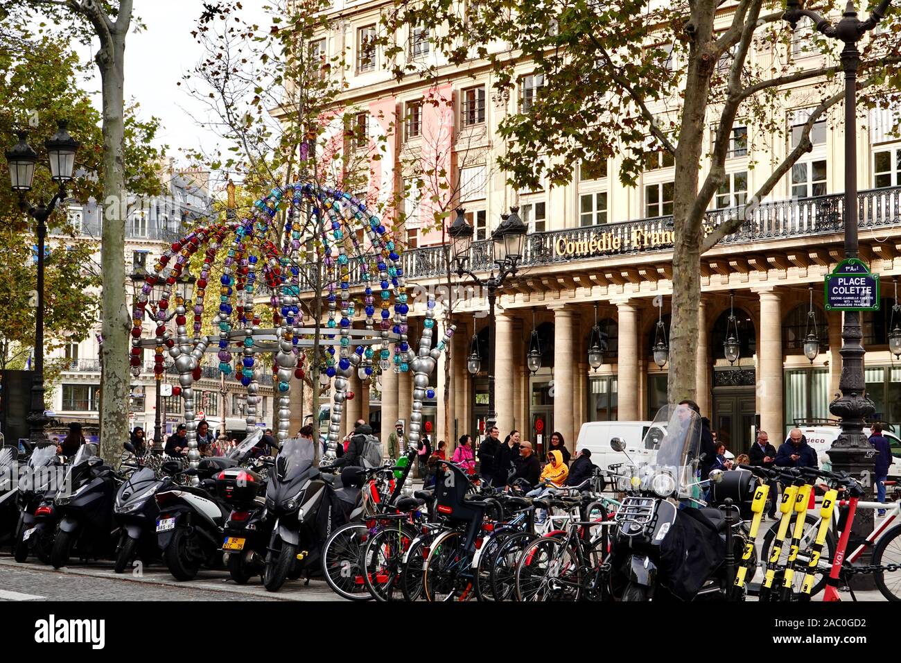 Persone, motociclette, biciclette e i colorati ingresso del metro a Place Colette, "Kiosque des noctambules' da Othoniel, Parigi, Francia. Foto Stock