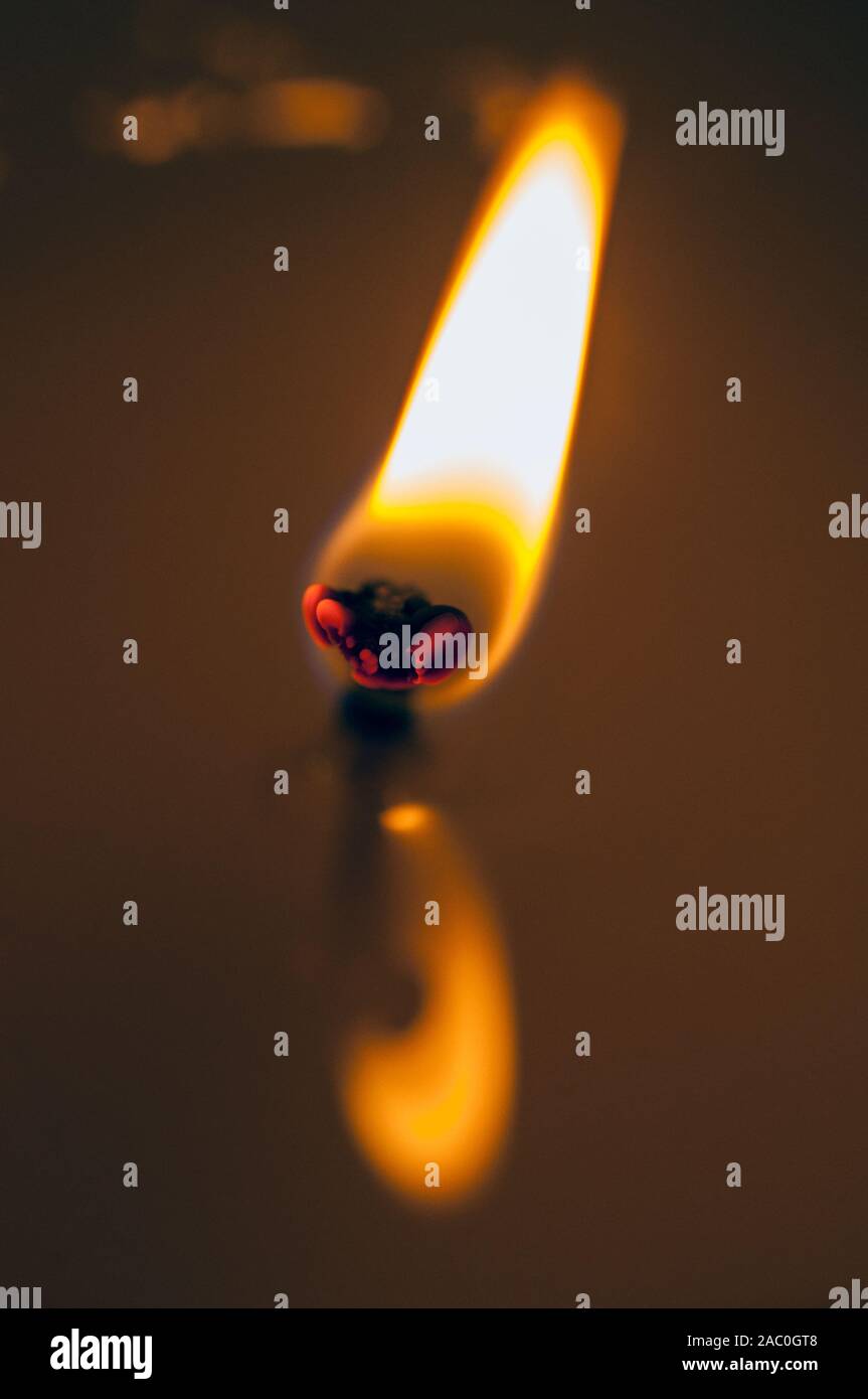 Extreme close-up della fiamma di una candela. La riflessione della fiamma nella candlewax fuso. Foto Stock