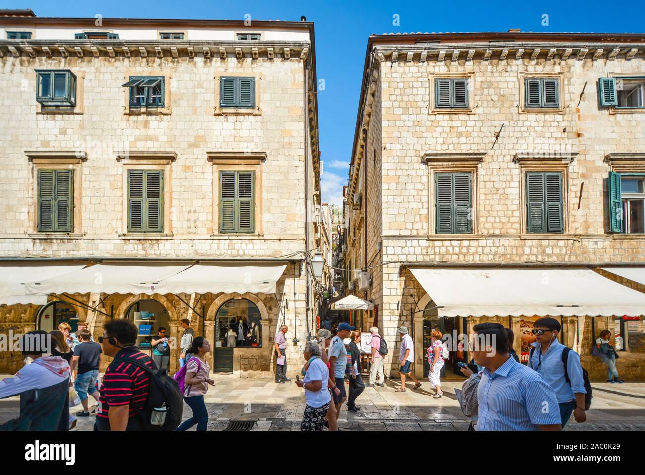 I turisti a piedi la strada principale o Stradun come essi passano una stretta scalinata fino alla parete nelle mura della città di Dubrovnik Croazia. Foto Stock