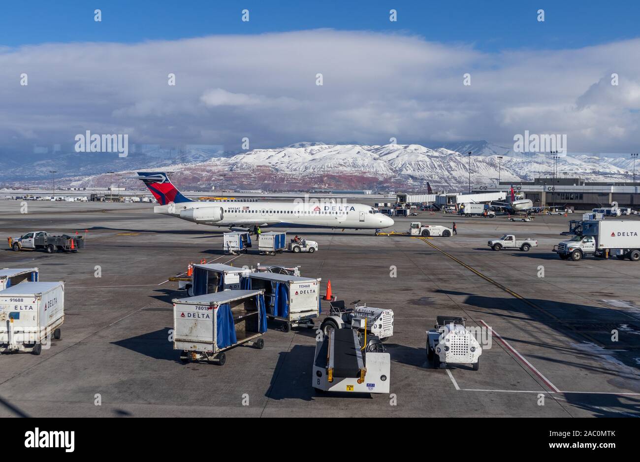 Velivoli Delta in rullaggio a Salt Lake City airport USA Utah, con gestori di terra sul piazzale con il bianco delle montagne innevate sullo sfondo Foto Stock