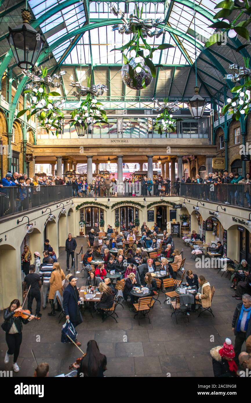 Il Covent Garden a tempo di Natale con le sue zone per mangiare, piani diversi e splendide decorazioni e tetto ad arco del vecchio mercato, Londra Foto Stock