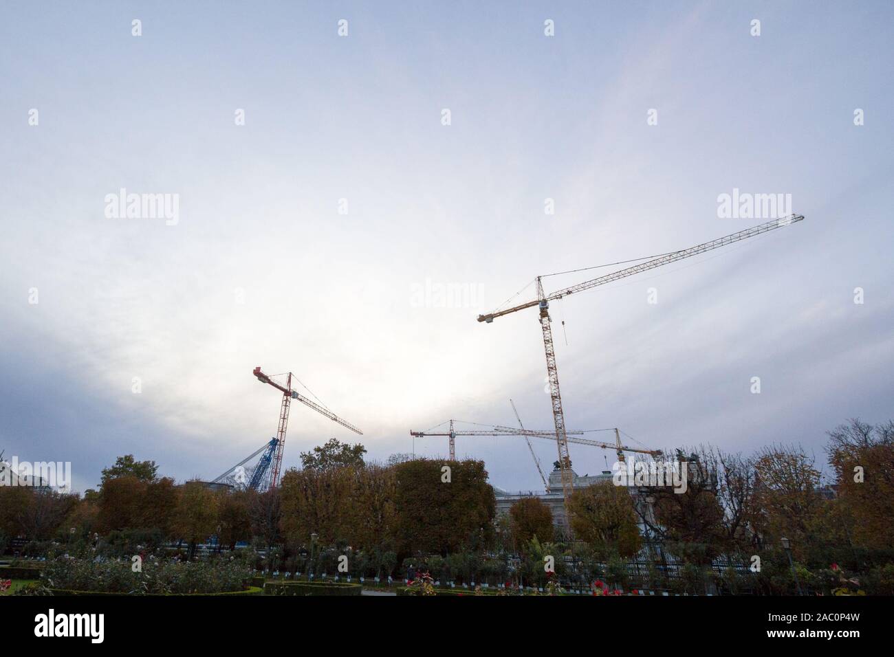 Gruppo di gru in un cantiere nel centro della città di Vienna, Austria, di fronte ad un edificio essendo assemblati presi da lontano durante una torbida e Foto Stock