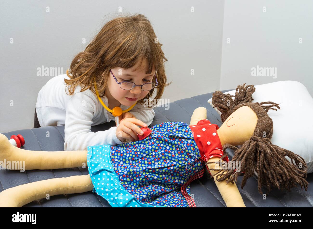 Bambino ragazza riproduzione medico con un giocattolo. Professione e il concetto di cura. Cancella sfondo neutro. Foto Stock