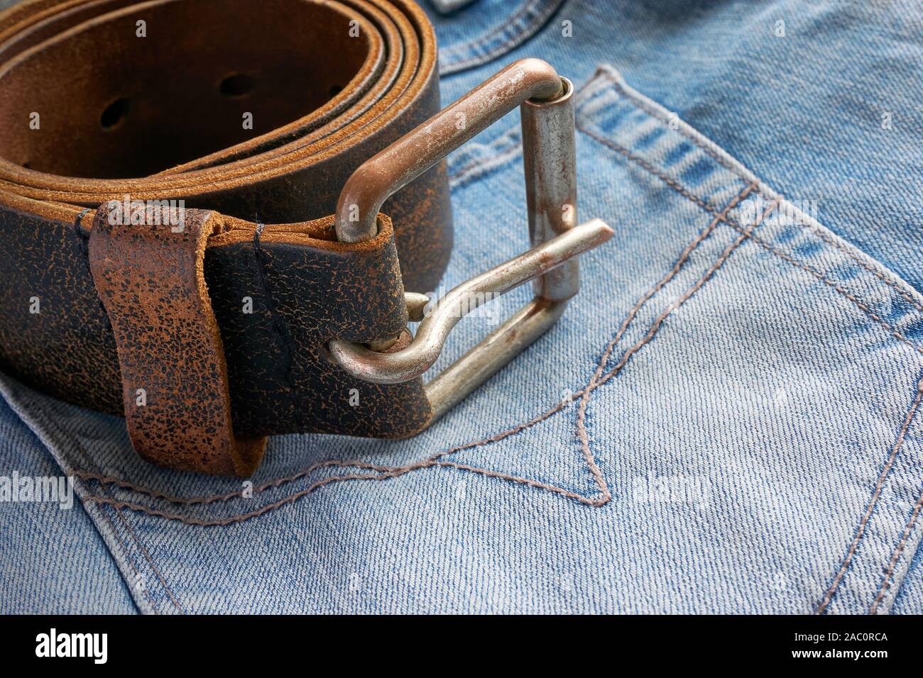 Marrone laminato cintura in cuoio con fibbia in metallo su blue jeans close-up Foto Stock