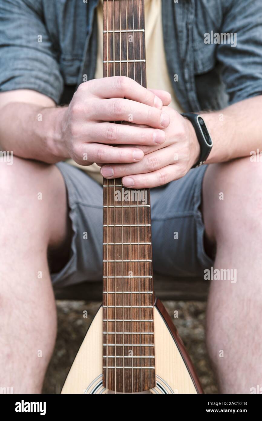 Gli uomini con le mani in mano tenere una chitarra acustica per il viaggio dietro un griff o collo. Foto Stock