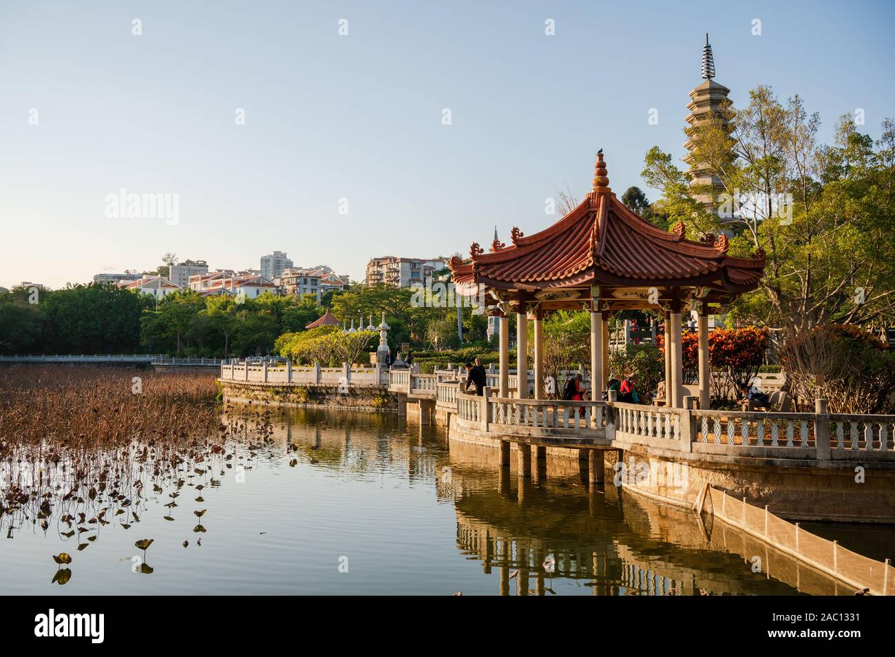 Padiglione accanto a uno stagno al Tempio di Nanputuo, isola di Xiamen, Cina visto in bagliore di tarda serata sole Foto Stock