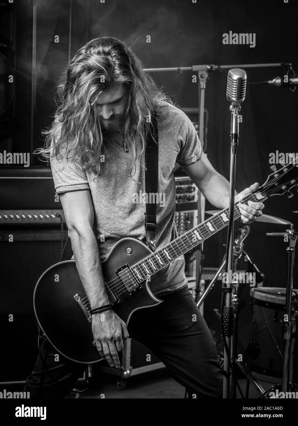 Foto di un giovane con capelli lunghi suonare la chitarra elettrica sul palco. Foto Stock