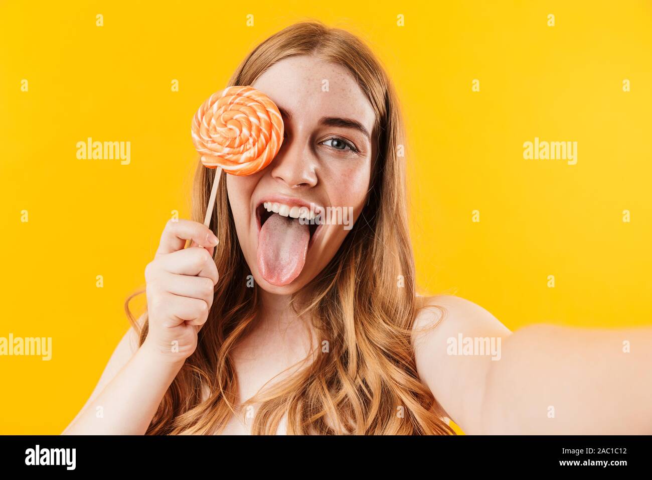 Immagine di un allegro lieto felice giovane carina ragazza adolescente in posa isolate su giallo sullo sfondo della parete di contenimento caramella dolce lollipop prendere selfie dalla fotocamera Foto Stock