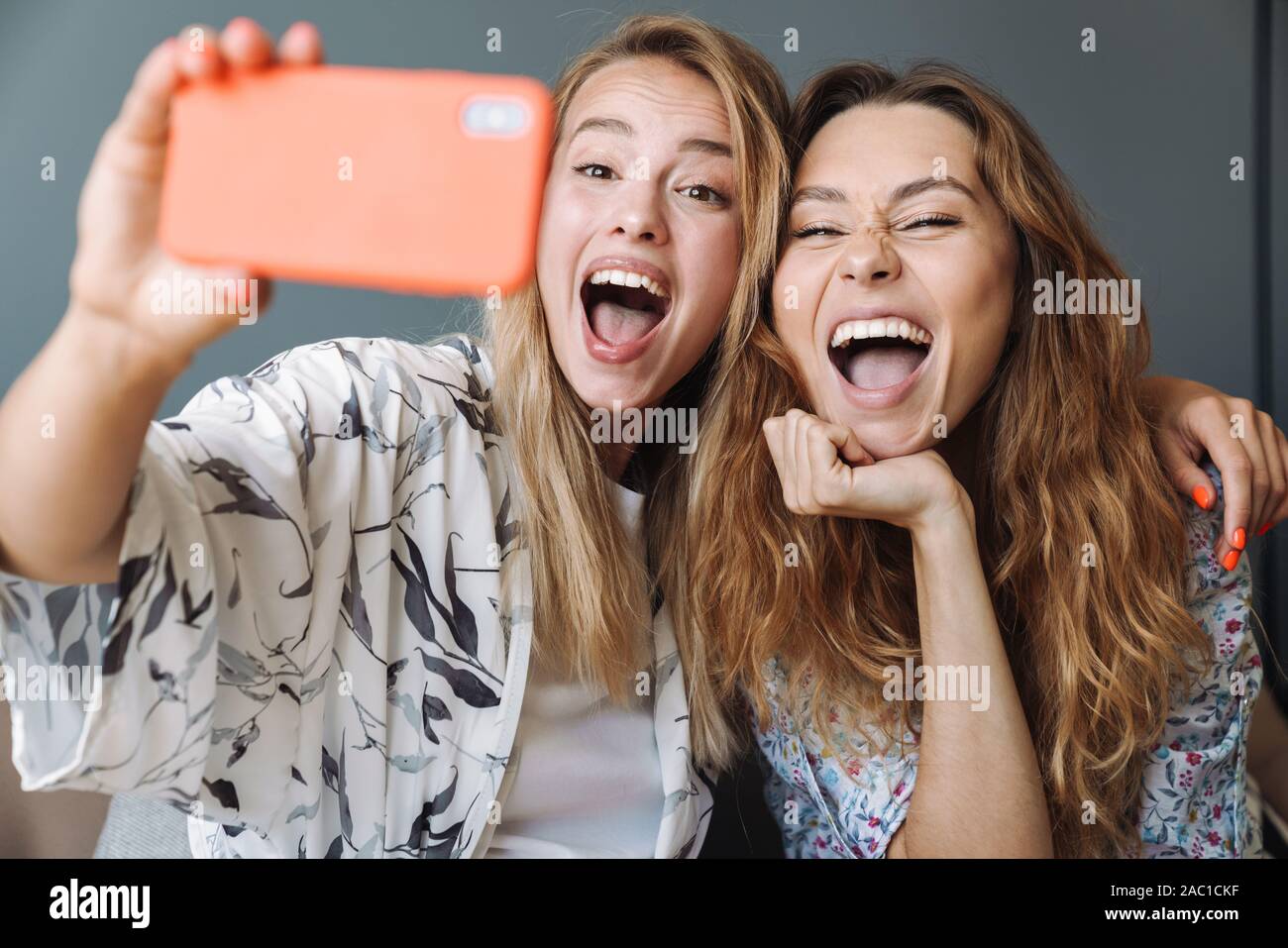 Foto della splendida urlando positiva delle donne di casa utilizzando il telefono cellulare prendere un selfie. Foto Stock