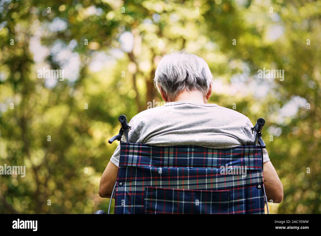 Vista posteriore di un anziano uomo seduto nella sedia a rotelle con la testa in giù Foto Stock