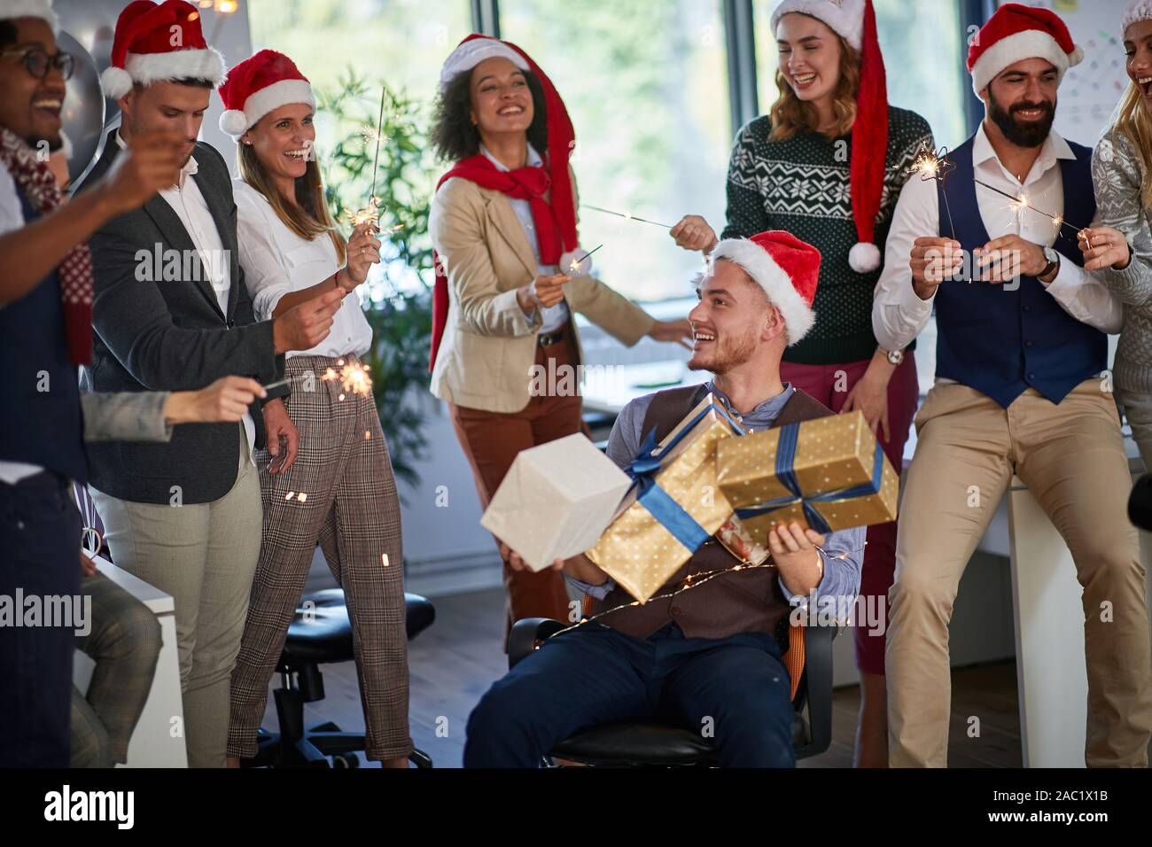 Xmas Party al lavoro. Felici i giovani imprenditori a santa con cappello di Natale presente Foto Stock