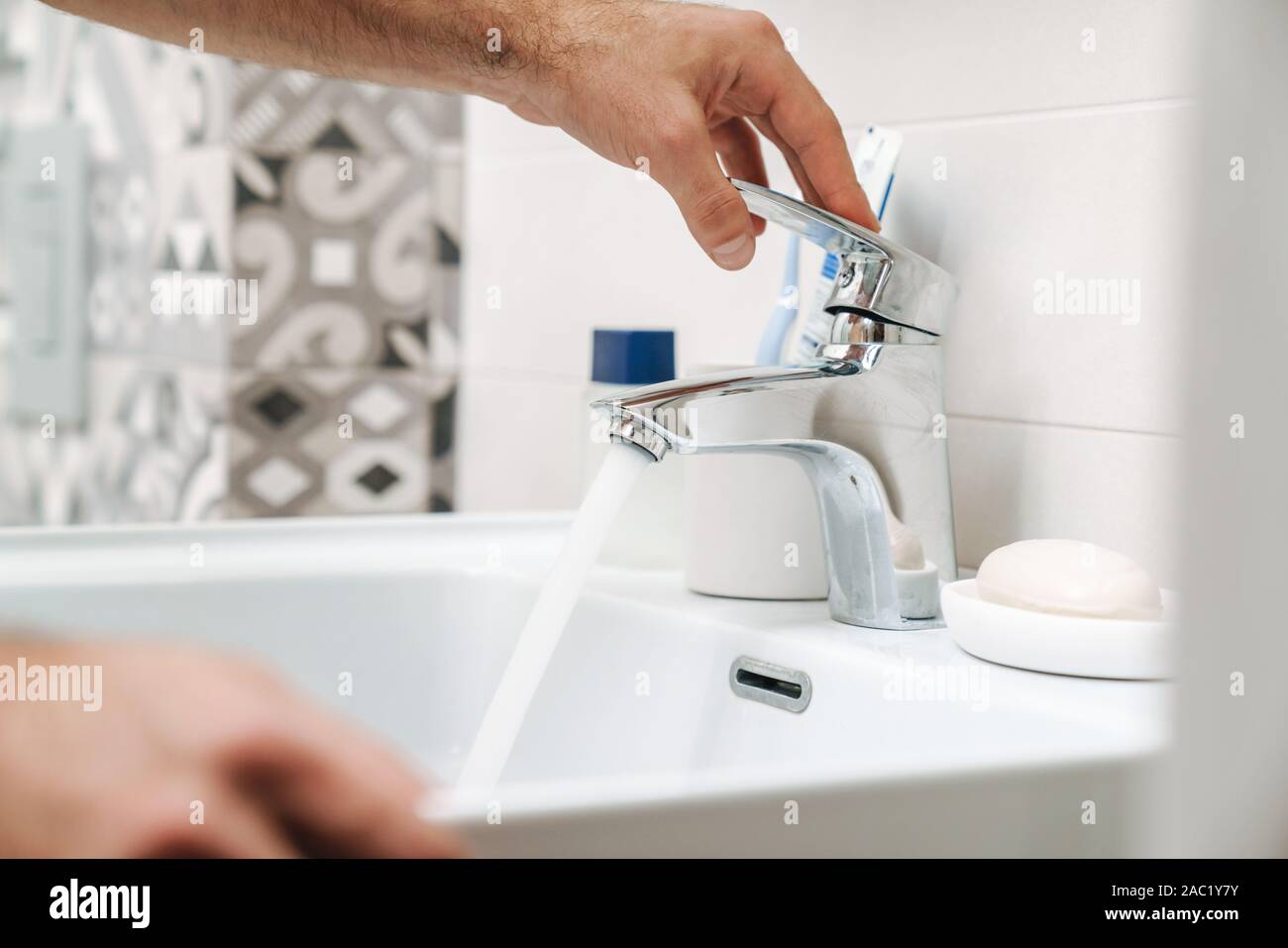 Close up di un uomo aprire il rubinetto al lavandino del bagno Foto Stock