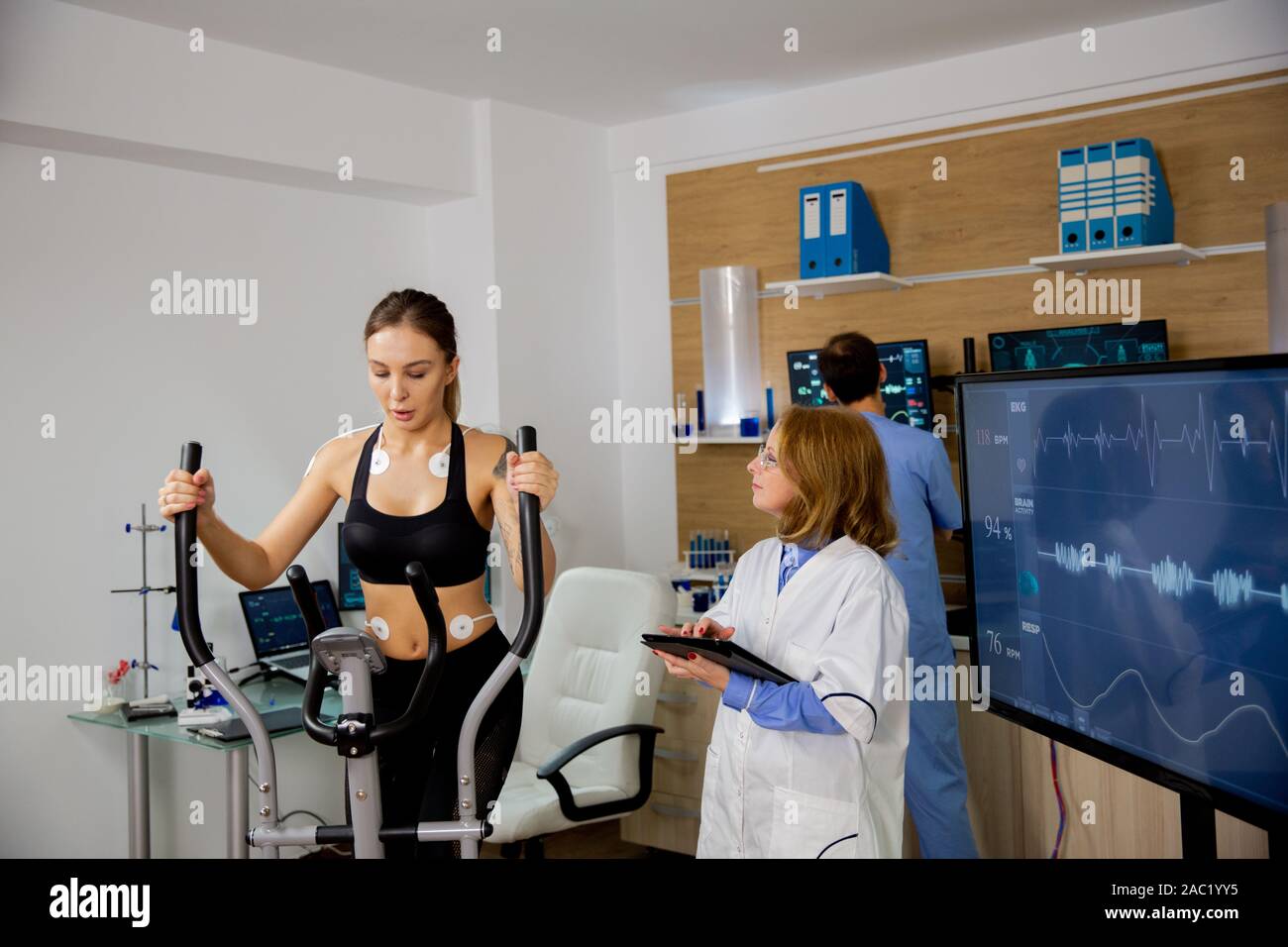 Atleta femminile facendo uno sforzo fisico sullo stepper e il medico segue il suo. Laboratorio di sport Foto Stock