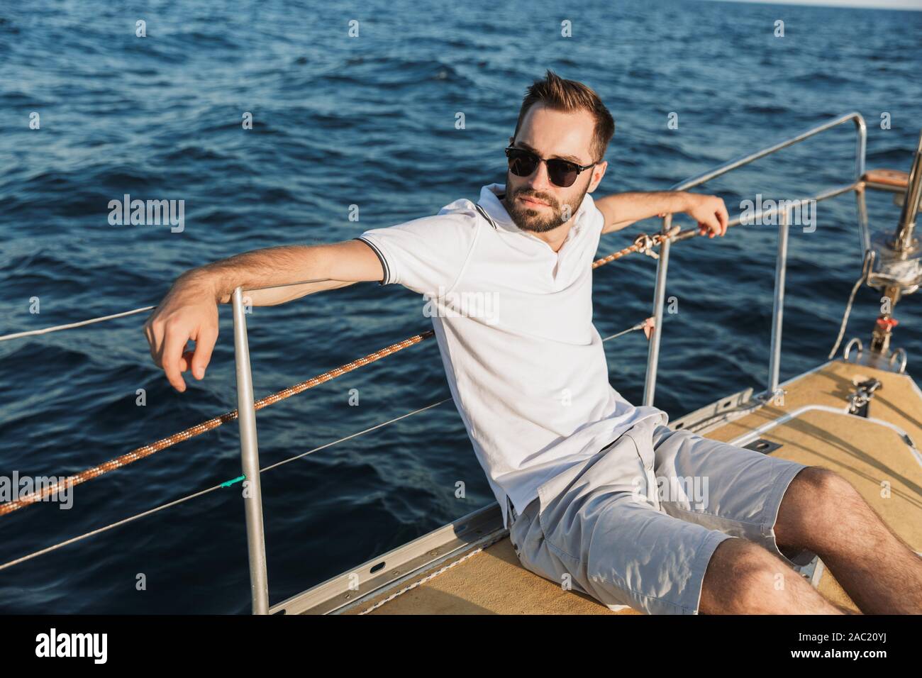 Immagine di grave bello attraente uomo all'aperto che posano su yacht in mare. Foto Stock