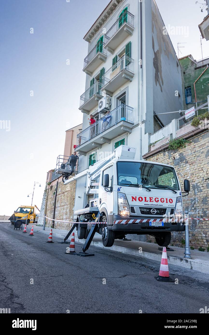 Ortona, Italia - 26 ottobre 2019: carrello con cesto per lavorare su edifici con operai al lavoro in Ortona Foto Stock