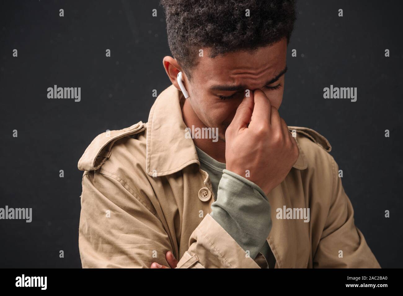 Immagine della infelice african american guy nel rivestire utilizzando earpods e pianto isolate su sfondo nero Foto Stock