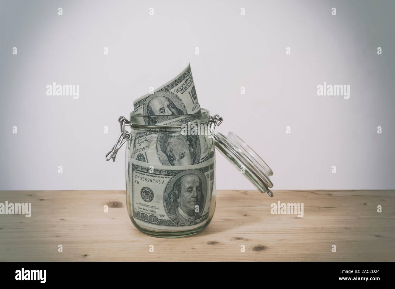 Le fatture del dollaro nel vasetto di vetro su un tavolo di legno. Risparmio di denaro concetto. Foto Stock