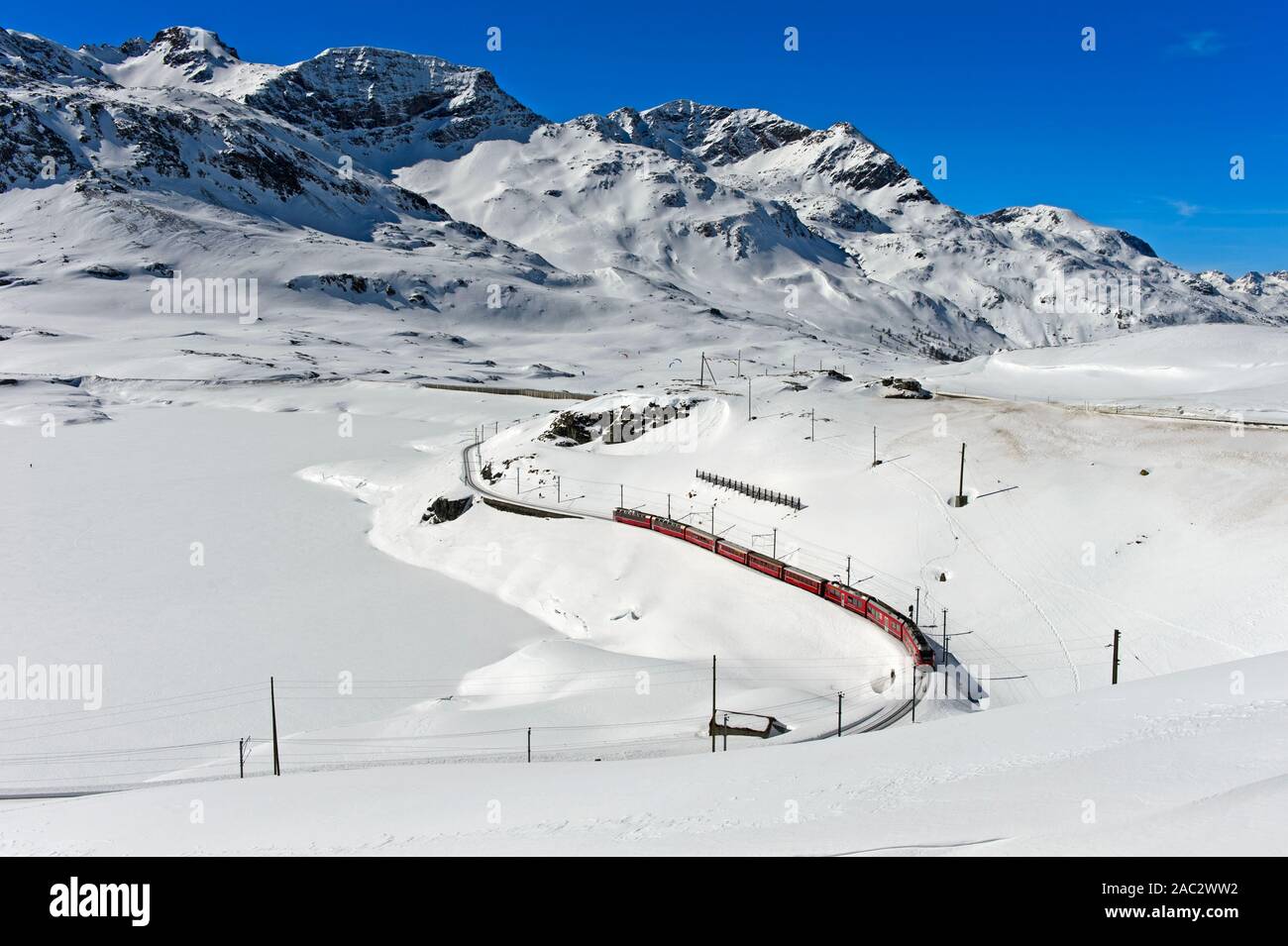 Percorso della Ferrovia Retica con il Bernina Express in invernale paesaggio alpino al Passo del Bernina, Engadina, Grigioni, Svizzera Foto Stock