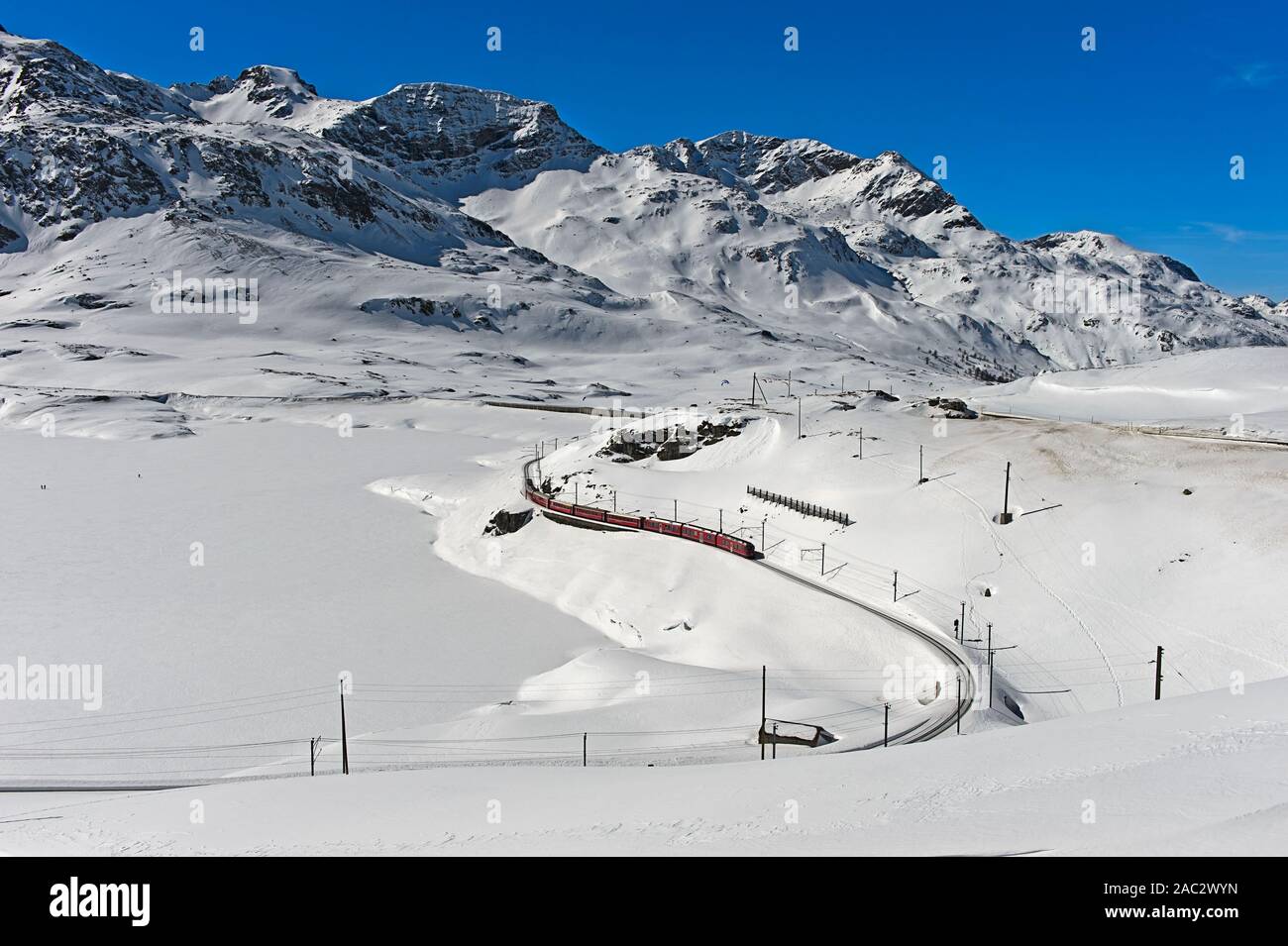 Percorso della Ferrovia Retica con il Bernina Express in invernale paesaggio alpino al Passo del Bernina, Engadina, Grigioni, Svizzera Foto Stock
