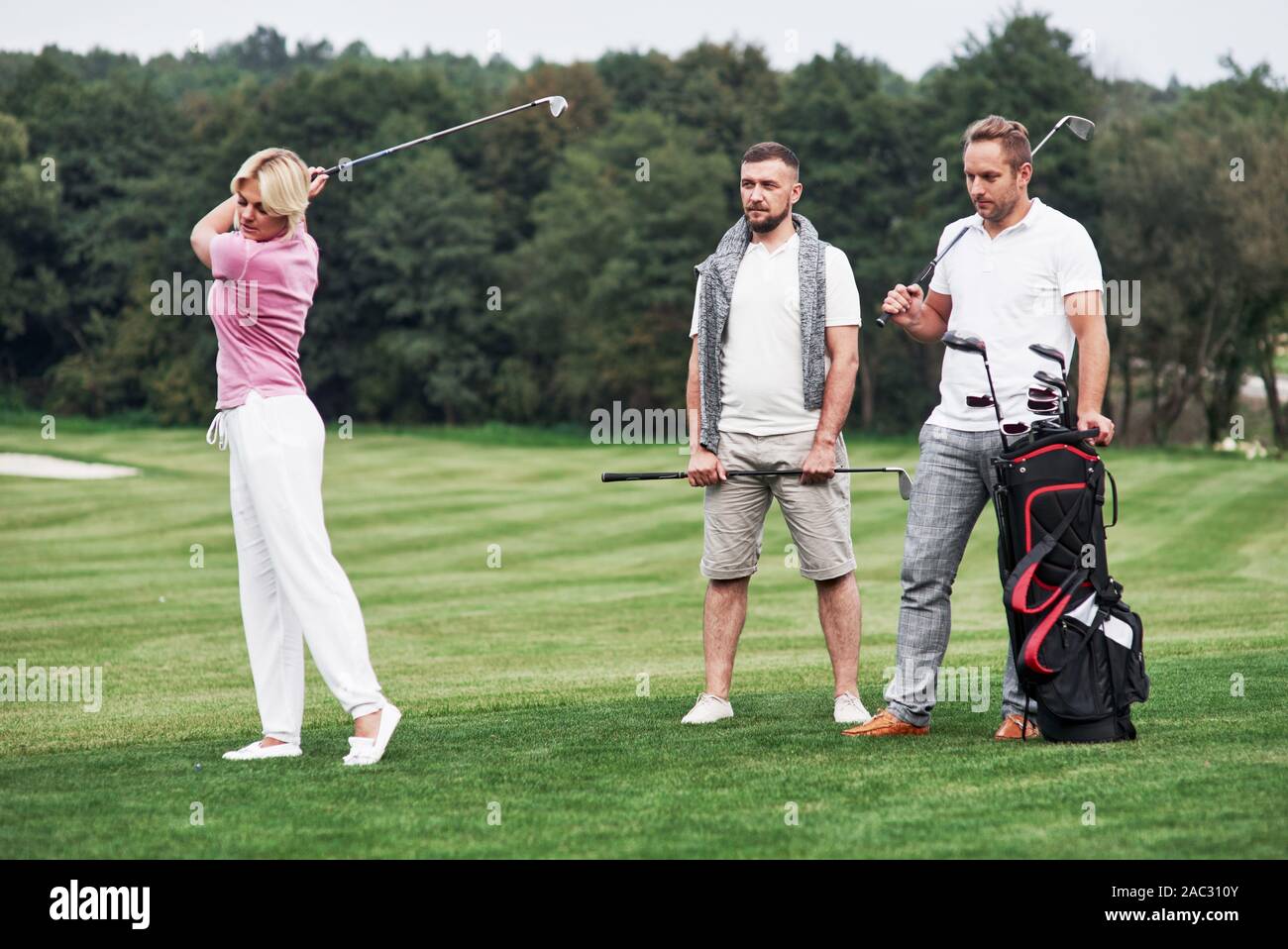 Tre amici di trascorrere un buon tempo in campo per giocare a golf e a guardare il tiro Foto Stock