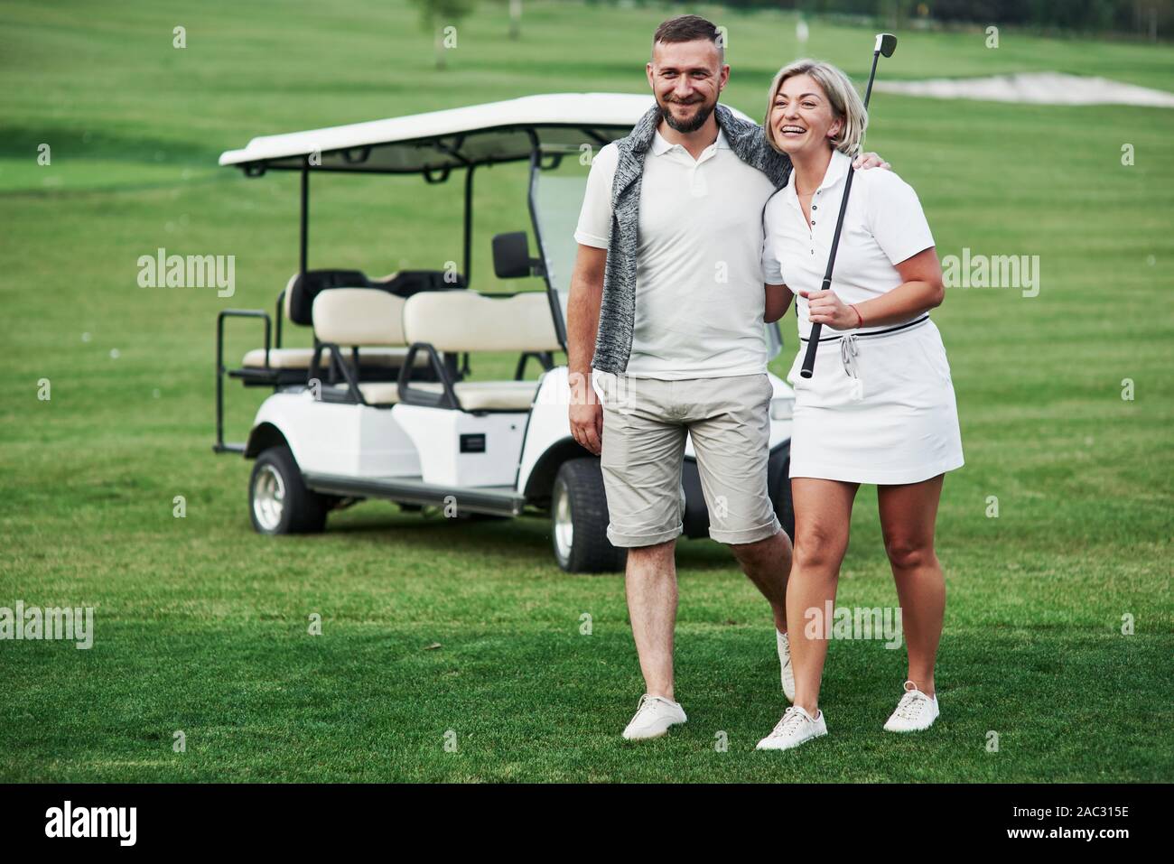 Sentirsi felice. Paio di due golfisti che soggiornano sul prato verde con carrello dietro di loro Foto Stock