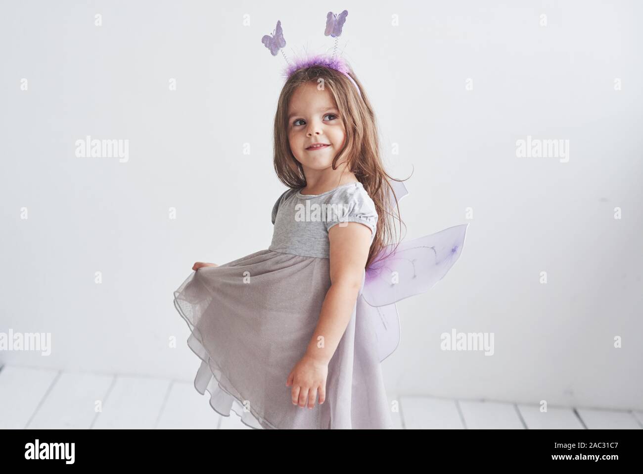 Look sognante. L immaginazione è cosa potente. Adorabile bambina in costume fata in piedi in camera con sfondo bianco Foto Stock