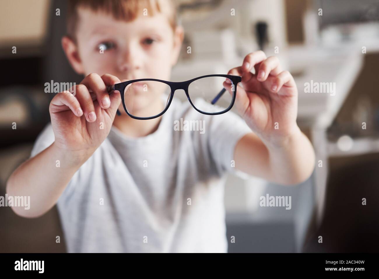 Foto focalizzato. Little Boy mantiene i suoi nuovi occhiali nell'ufficio del medico Foto Stock