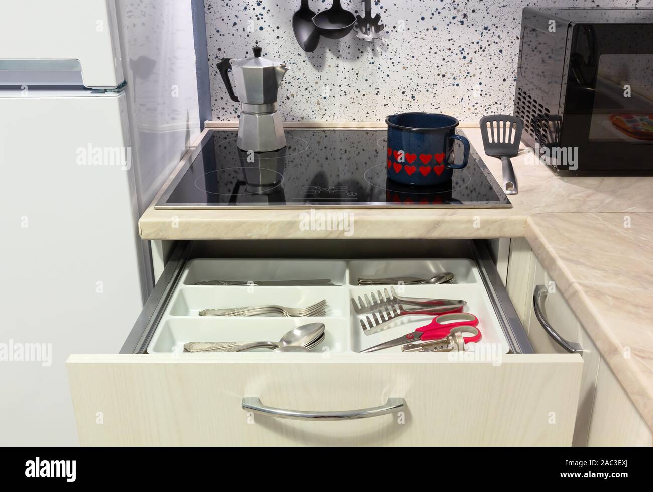 Aprire il cassetto in una cucina moderna con un bollitore e una macchinetta per il caffè sul piano cottura Foto Stock