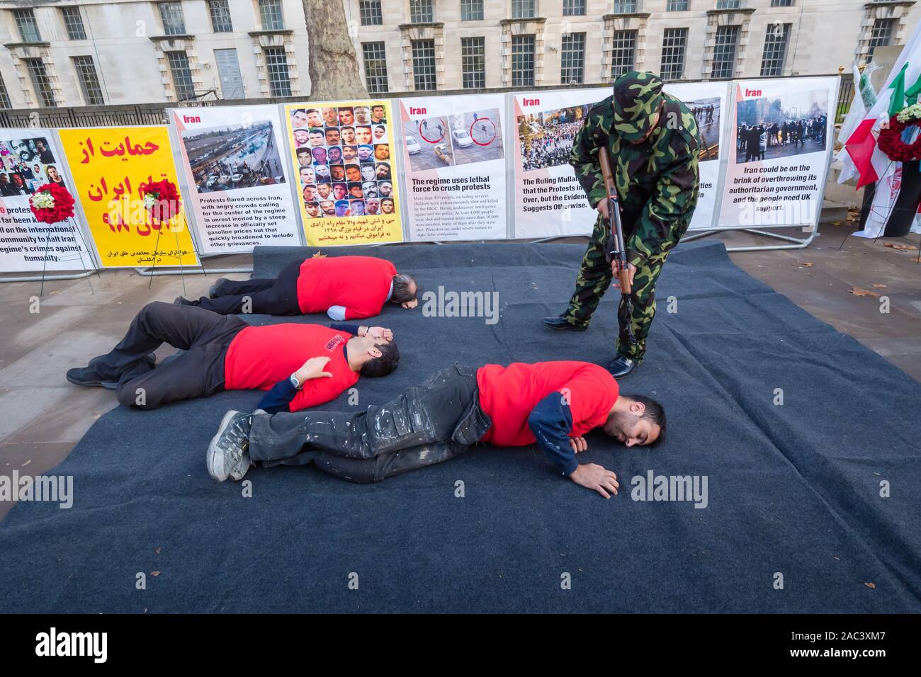 Londra, Regno Unito. 30 Novembre, 2019. Attori ri-emanare le riprese di manifestanti da iraniani le forze di sicurezza in un rally da Anglo-Iranian europee nel Regno Unito e sostenitori dei mujaheddin del popolo dell'Iran del consiglio nazionale della resistenza iraniana a Downing St a sostegno delle proteste in Iran contro il regime clericale. Oltre 450 manifestanti sono stati uccisi nella repressione brutale dell'Iran proteste da parte delle forze di sicurezza, con 4000 feriti e migliaia arrestati. Credito: Peter Marshall / Alamy Live News Foto Stock