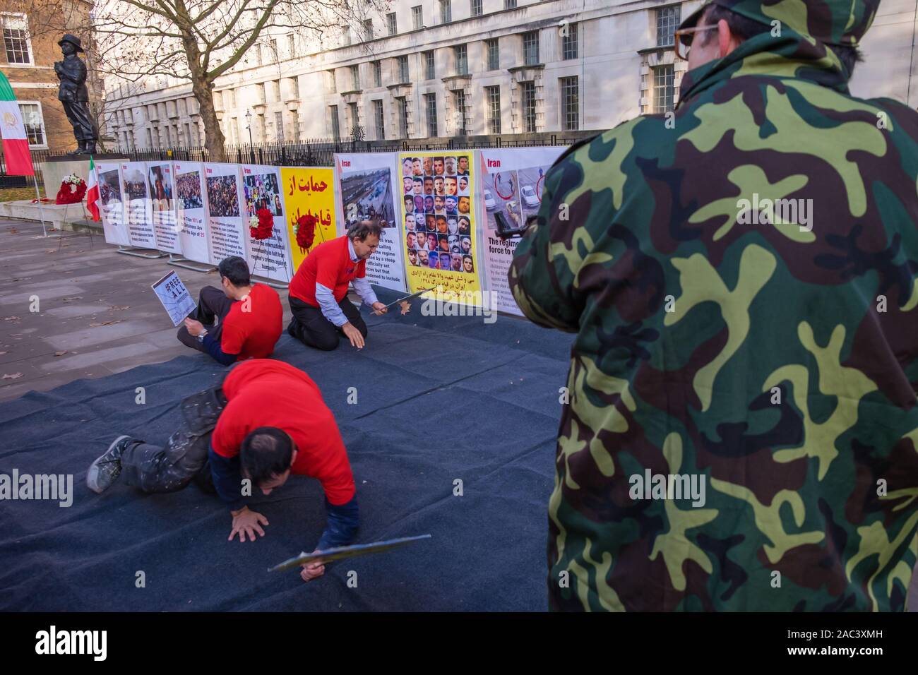 Londra, Regno Unito. 30 Novembre, 2019. Attori ri-emanare le riprese di manifestanti da iraniani le forze di sicurezza in un rally da Anglo-Iranian europee nel Regno Unito e sostenitori dei mujaheddin del popolo dell'Iran del consiglio nazionale della resistenza iraniana a Downing St a sostegno delle proteste in Iran contro il regime clericale. Oltre 450 manifestanti sono stati uccisi nella repressione brutale dell'Iran proteste da parte delle forze di sicurezza, con 4000 feriti e migliaia arrestati. Credito: Peter Marshall / Alamy Live News Foto Stock
