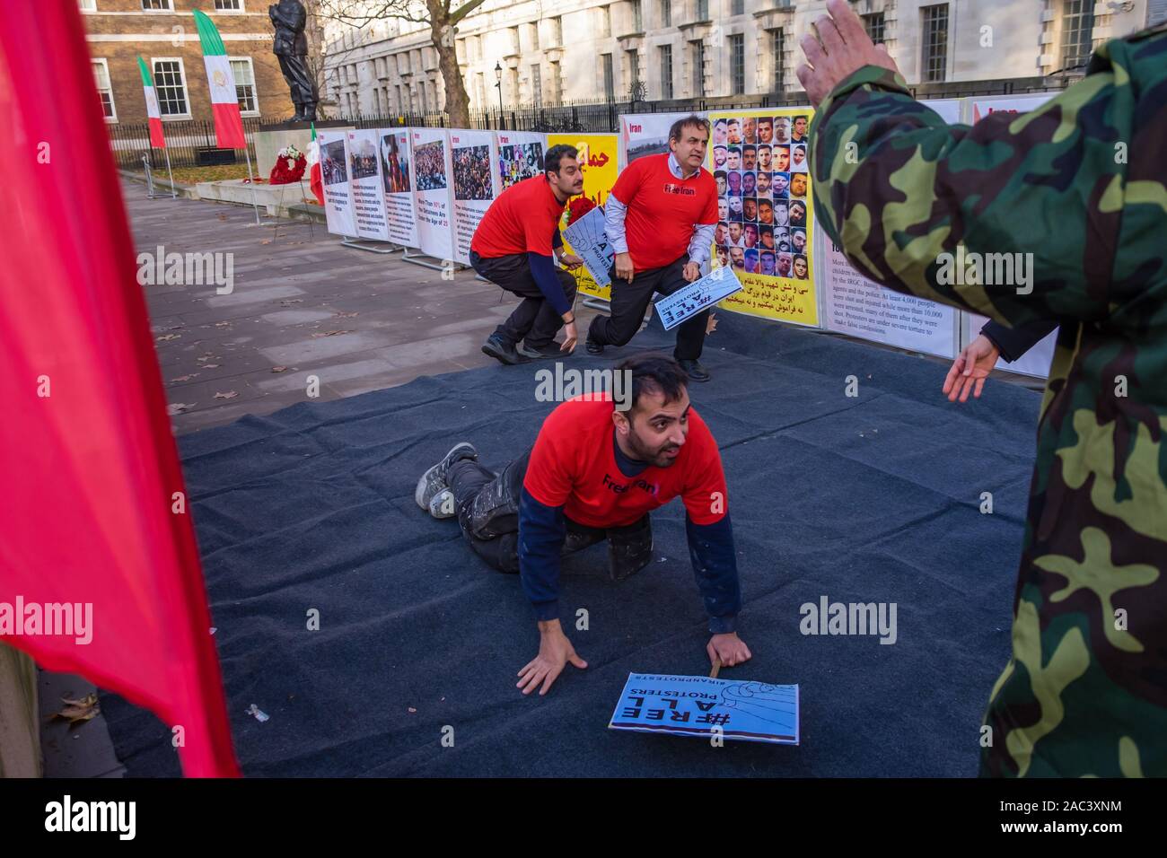 Londra, Regno Unito. 30 Novembre, 2019. Attori ri-emanare le riprese di manifestanti da iraniani le forze di sicurezza in un rally da Anglo-Iranian europee nel Regno Unito e sostenitori dei mujaheddin del popolo dell'Iran del consiglio nazionale della resistenza iraniana a Downing St a sostegno delle proteste in Iran contro il regime clericale. Oltre 450 manifestanti sono stati uccisi nella repressione brutale dell'Iran proteste da parte delle forze di sicurezza, con 4000 feriti e migliaia arrestati. Credito: Peter Marshall / Alamy Live News Foto Stock