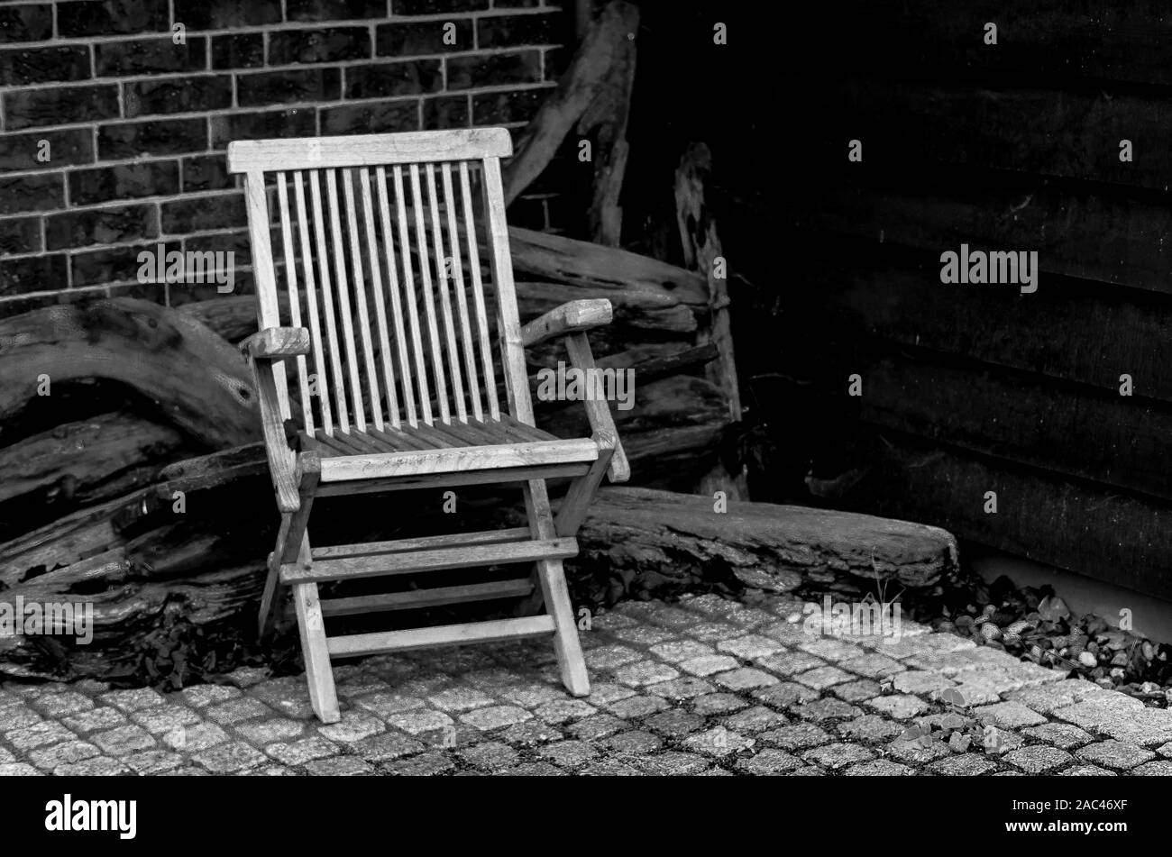 Vuota la sedia in legno, sfondo da vecchi pezzi di legno, la parete laterale da listoni. Foto in bianco e nero, in stile retrò. Foto Stock