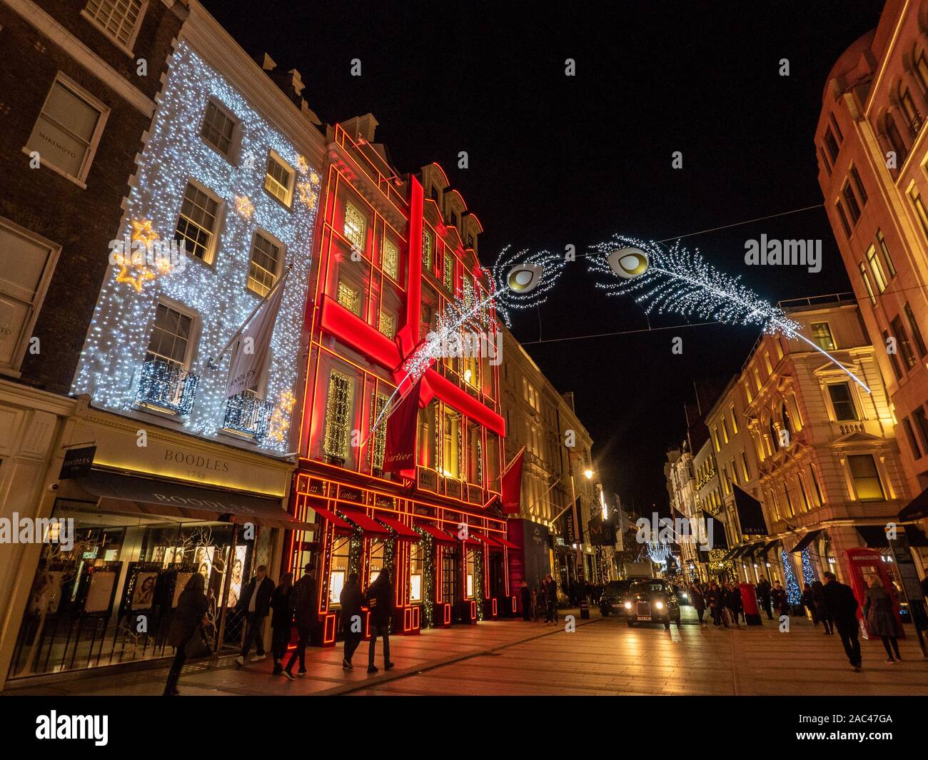 Luci festive in New Bond Street di notte con la facciata rossa di Cartier, Mayfair, Londra. Foto Stock