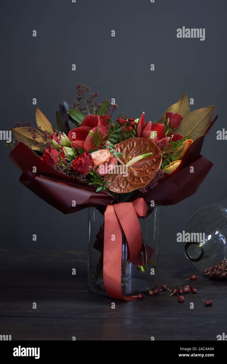 Elegante bouquet di autunno in rosso i colori in stile vintage in un vaso di vetro e un grande vaso di estratto secco di rosa canina su uno sfondo scuro, il fuoco selettivo Foto Stock