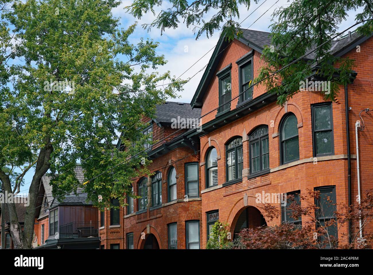 Viale alberato con grandi vecchie case in mattoni con gables Foto Stock