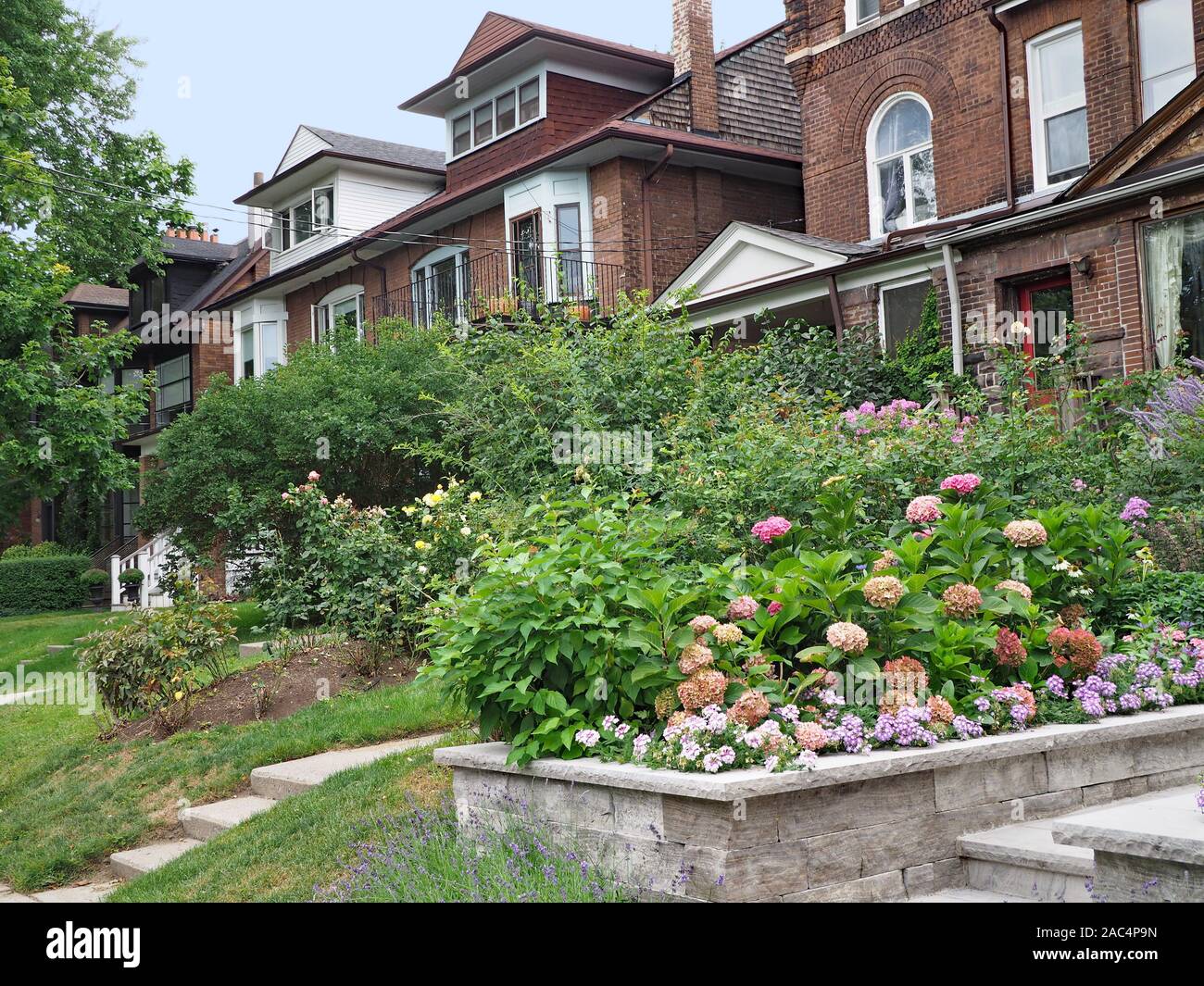 Strada residenziale con vecchie case in mattoni e cantieri anteriore con fiori colorati Foto Stock