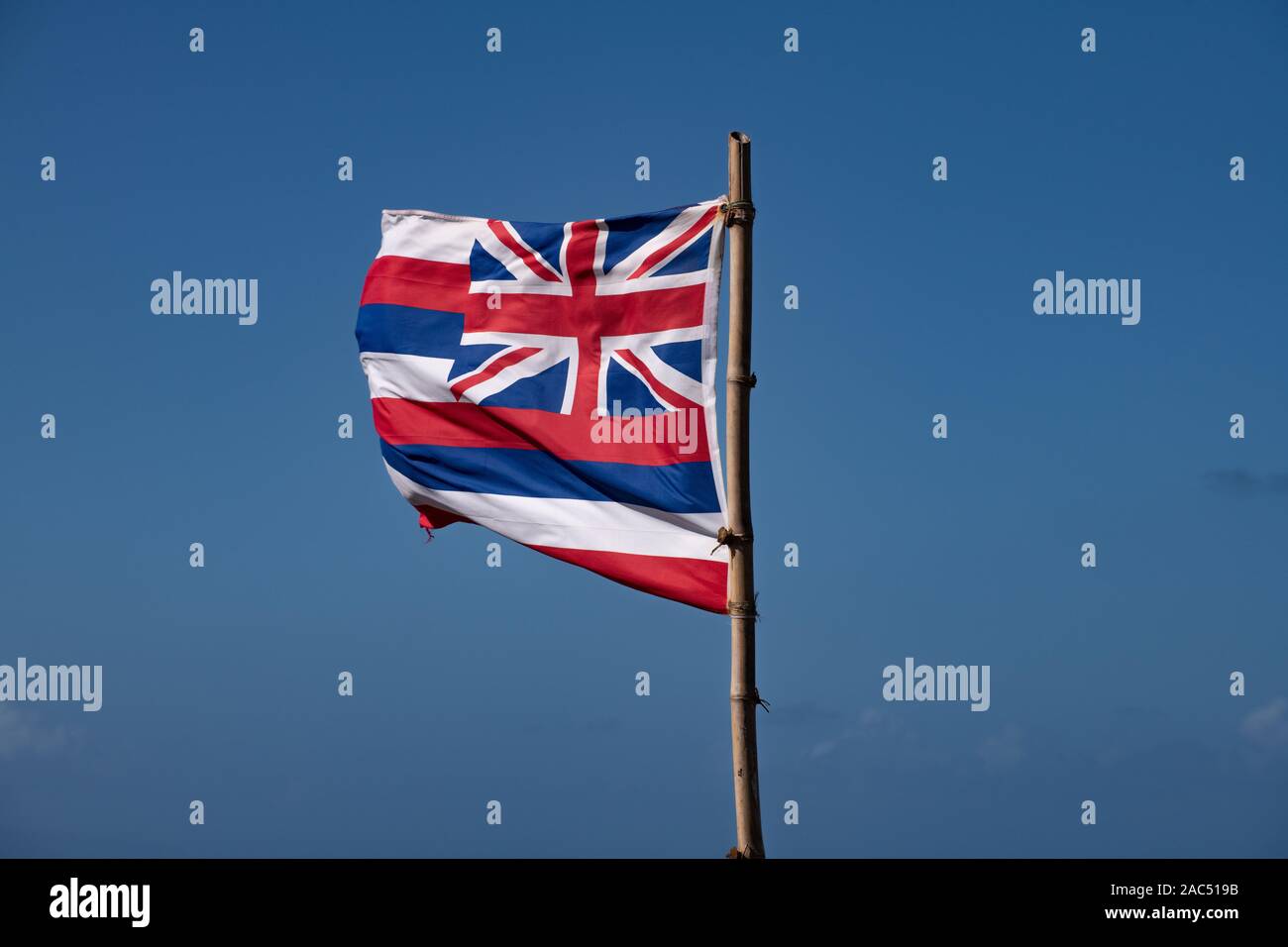 Bandiera hawaiiana che fluttua nel vento contro un cielo blu Foto Stock