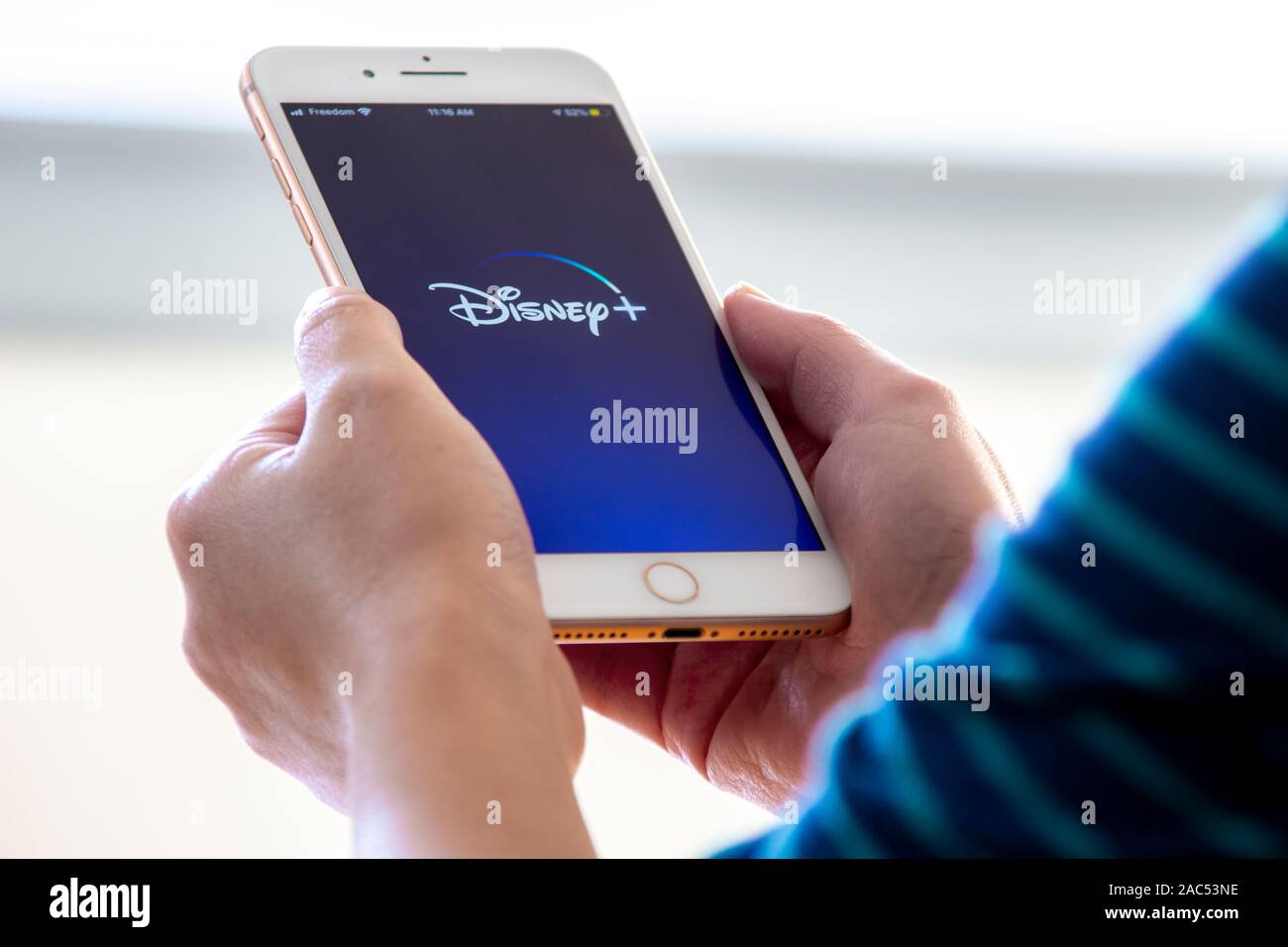 Calgary, Alberta. Canada Nov 28 2019: Donna possiede un iphone plus con il nuovo Disney+ app sulle mani. Disney+ rilasciare un nuovo aggiornamento del suo vid online Foto Stock