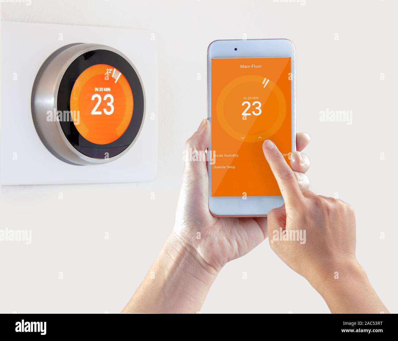 Termostato intelligente e una persona che configura la temperatura smart device tenere in mano su sfondo bianco Foto Stock