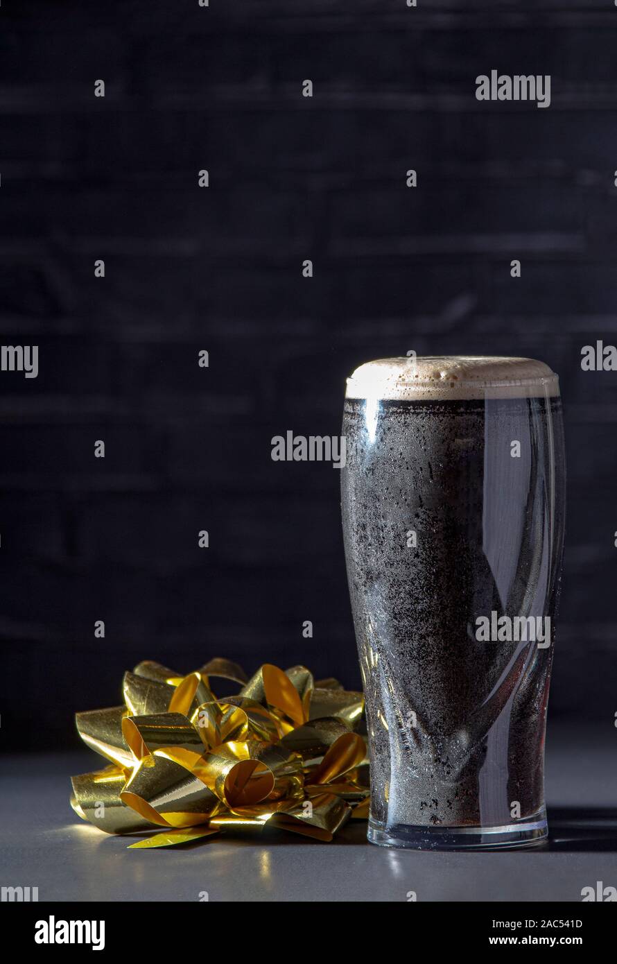 Un buio Irish dry stout birra di vetro con un nastro in regalo Foto Stock