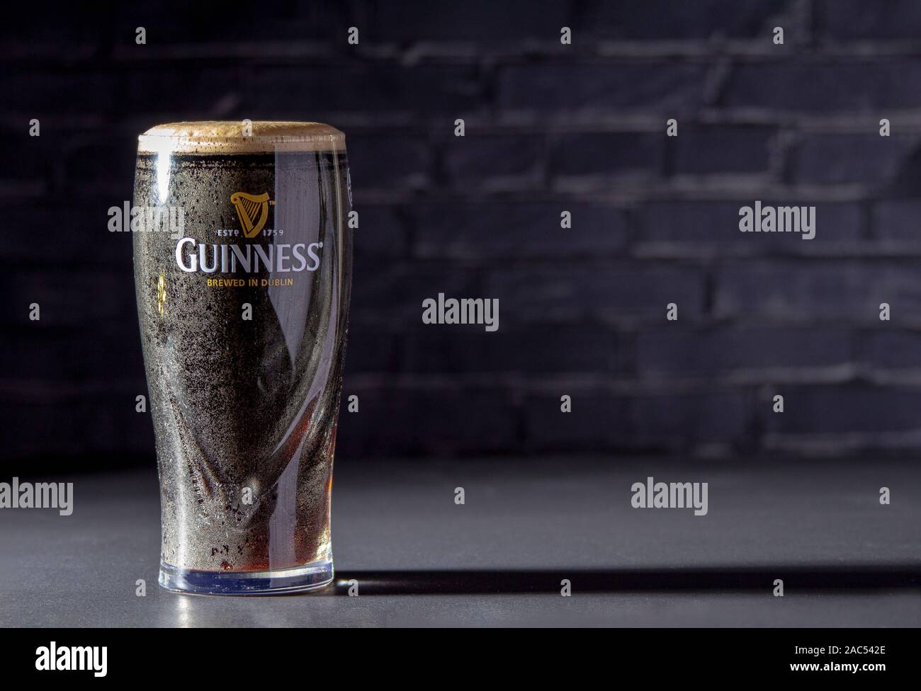 Calgary AB, Canada. Novembre 26, 2019. Un buio Irish Stout secca bicchiere di birra con un mattone nero su sfondo Foto Stock