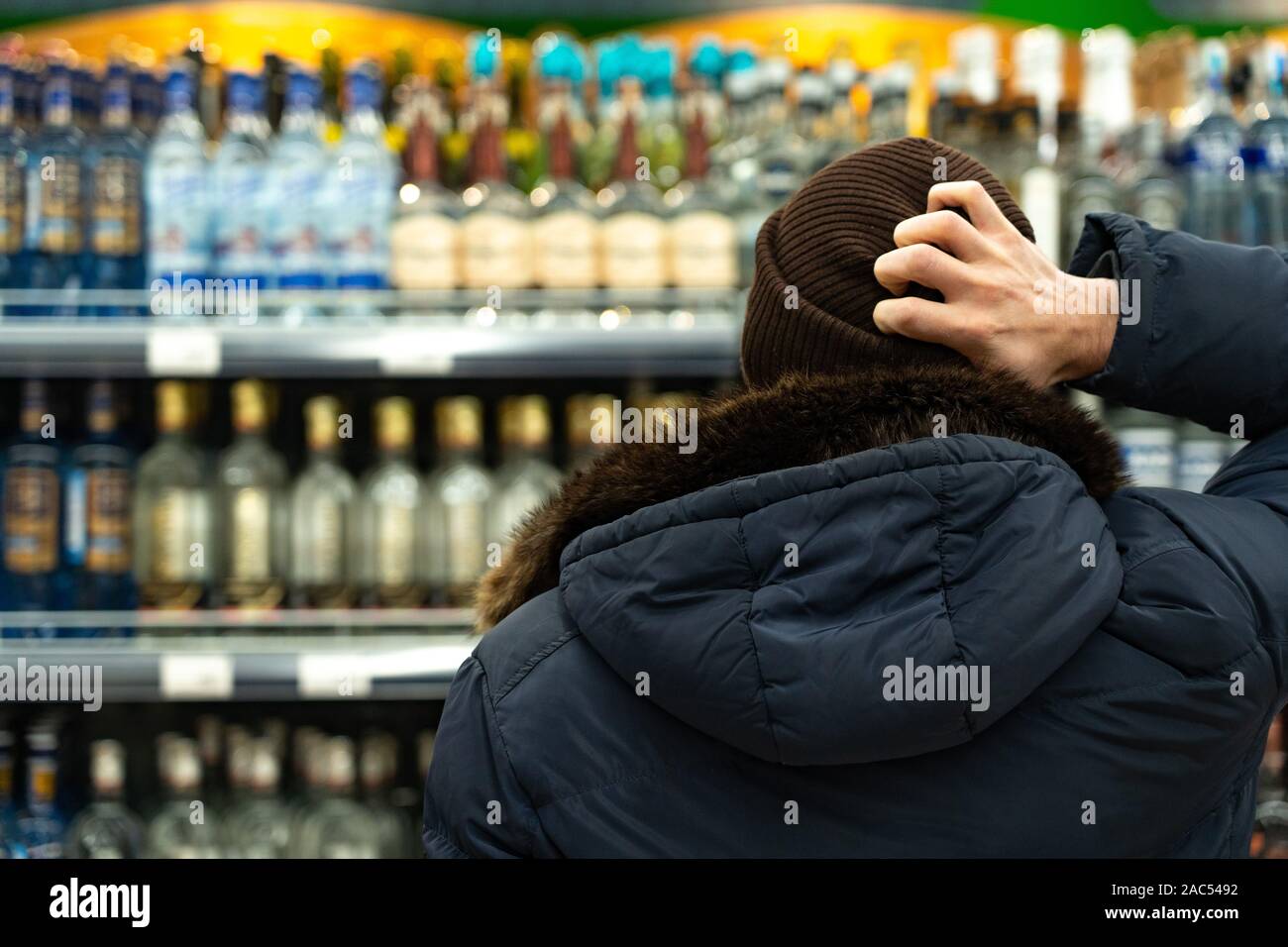 Ekaterinburg, Russia - Novembre 2019. Un uomo di pensiero nella parte anteriore delle righe di alcool in un supermercato. Una vasta gamma di bevande alcoliche. Il buy Foto Stock