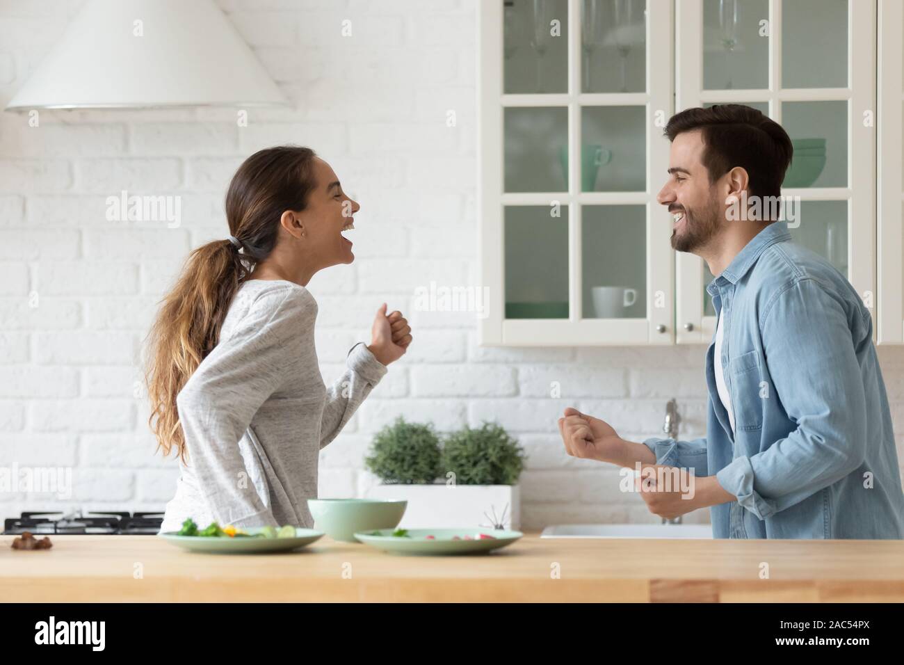Attivo felice coppia giovane divertirsi ballare insieme in cucina Foto Stock