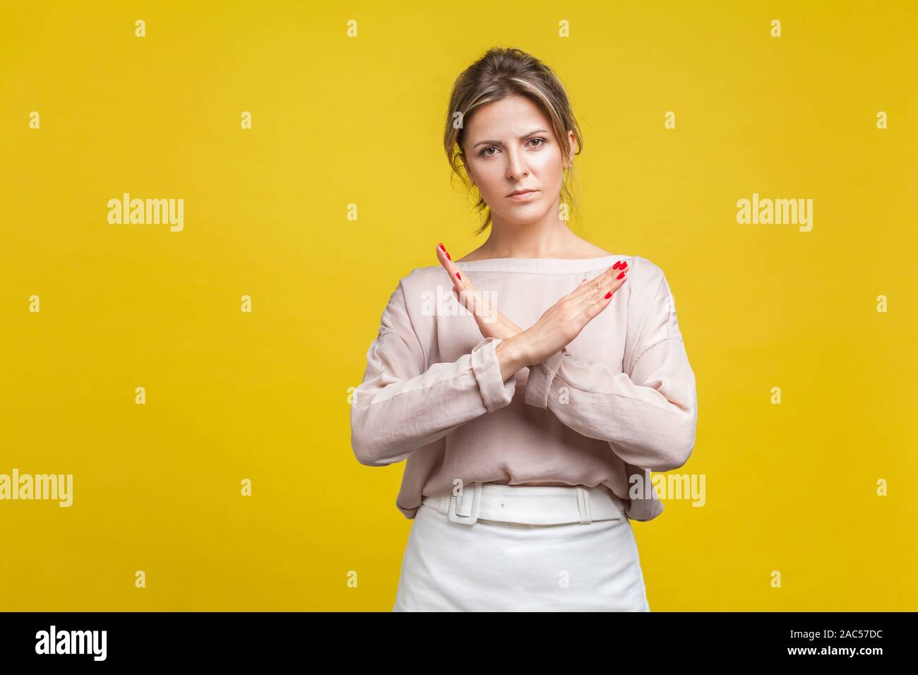 Non più, questa è la fine. Ritratto di grave testardo giovane donna con capelli biondi nella camicia casual che mostra permanente gesto chiuso con due mani incrociate. Foto Stock